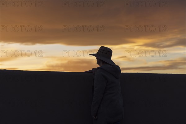 Silhouette of man in hat looking at sunset