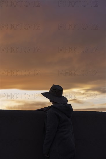 Silhouette of man in hat looking at sunset