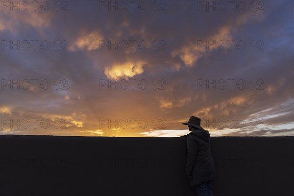 Silhouette of man in hat looking at sunset