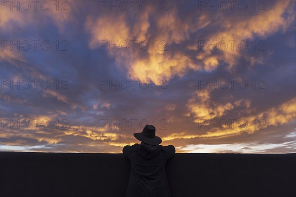 Silhouette of man in hat looking at sunset