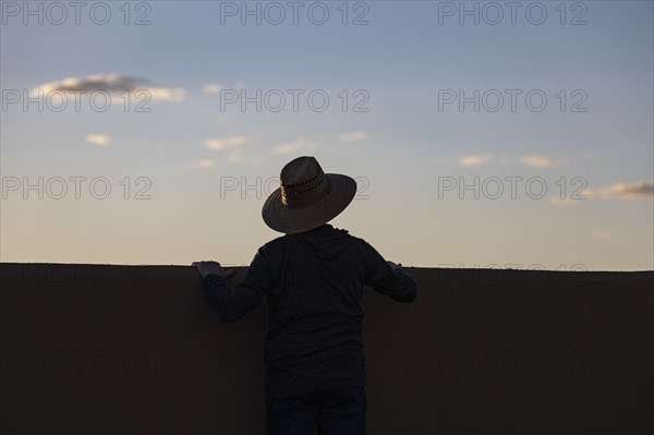 Silhouette in hat looking at sunset