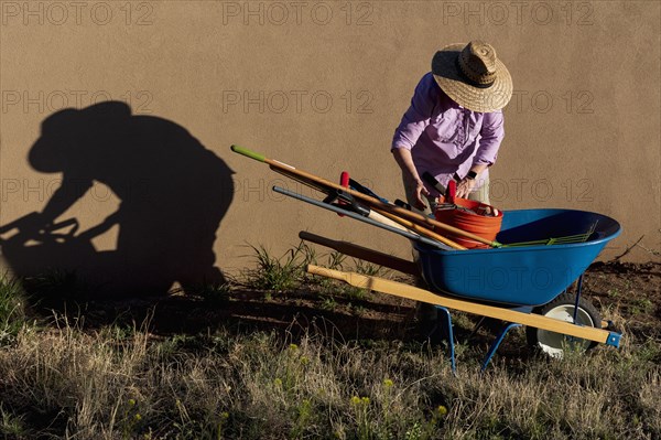 Senior woman with gardening equipment in desert garden