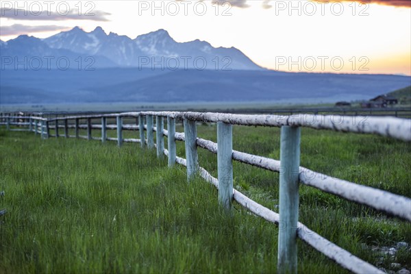 Scenic view of Sawtooth Mountains and meadow with rail fence at sunset