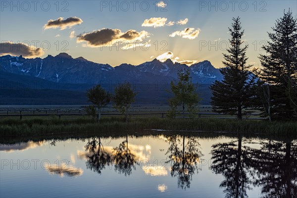 Scenic view of Sawtooth Mountains with pond at sunset