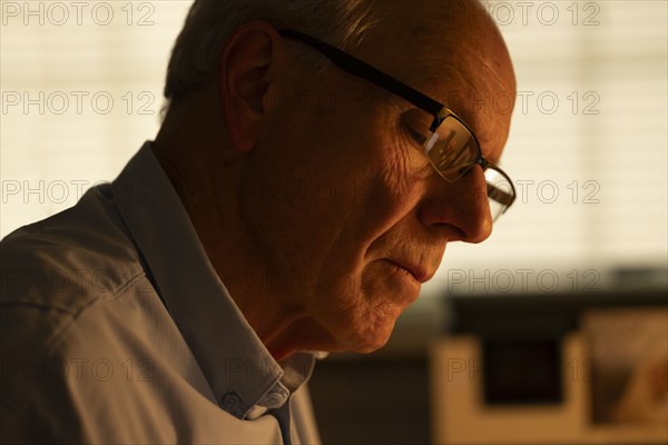 Portrait of thoughtful senior man looking down at home