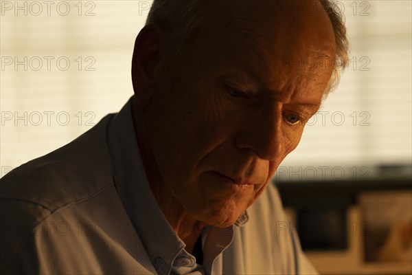 Portrait of thoughtful senior man looking down at home