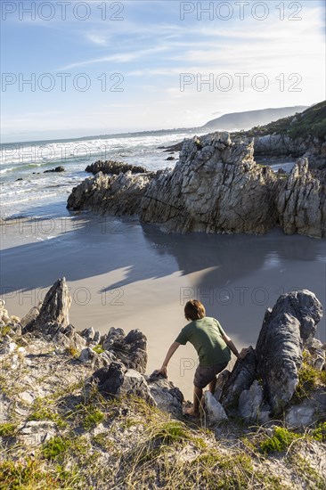 Boy exploring rocky coastline in Voelklip Beach
