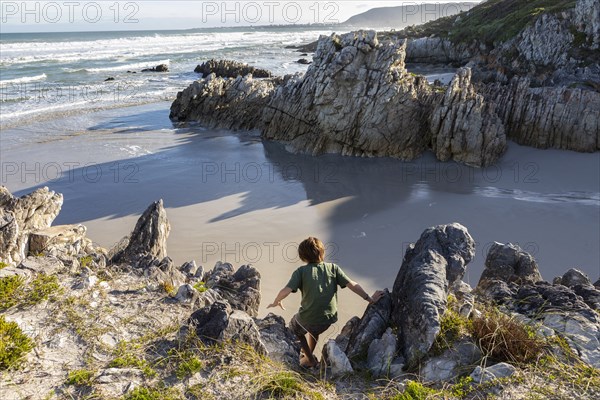 Boy exploring rocky coastline in Voelklip Beach