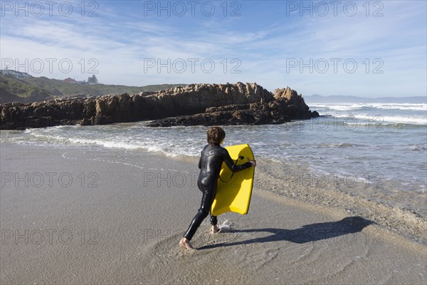 Boy entering Atlantic Ocean with body board in Kammabaai Beach