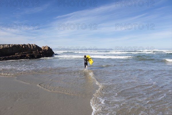 Boy entering Atlantic Ocean with body board in Kammabaai Beach