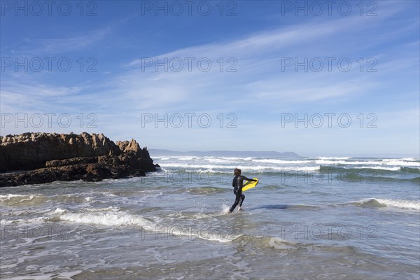 Boy entering Atlantic Ocean with body board in Kammabaai Beach