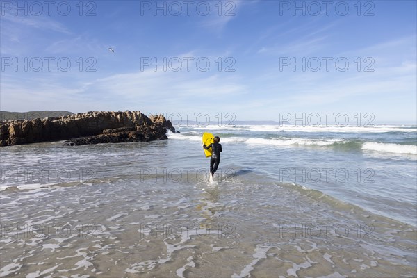 Boy entering Atlantic Ocean with body board in Kammabaai Beach