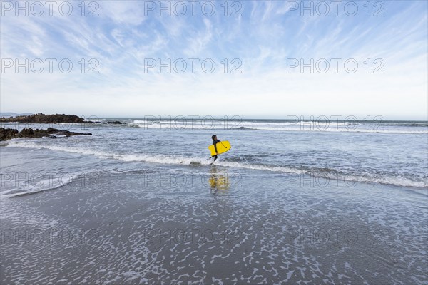 Boy entering Atlantic Ocean with body board