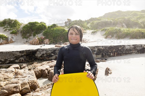 Portrait of boy standing with body board