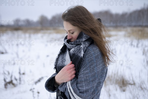 Portrait of freezing woman standing in snowy meadow