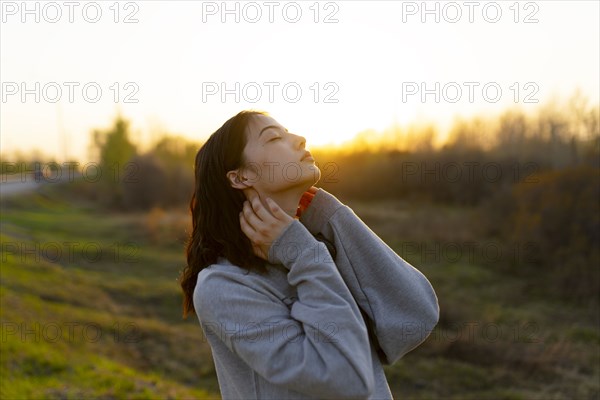 Portrait of thoughtful woman with closed eyes in meadow at sunset