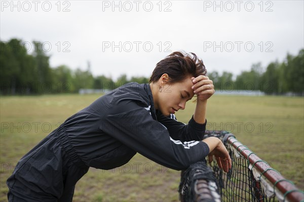 Side view of young woman leaning on mini soccer goal