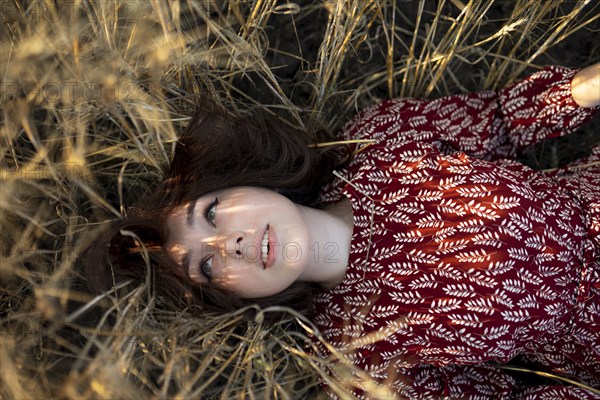 Directly above view of woman lying on cereal plants in field