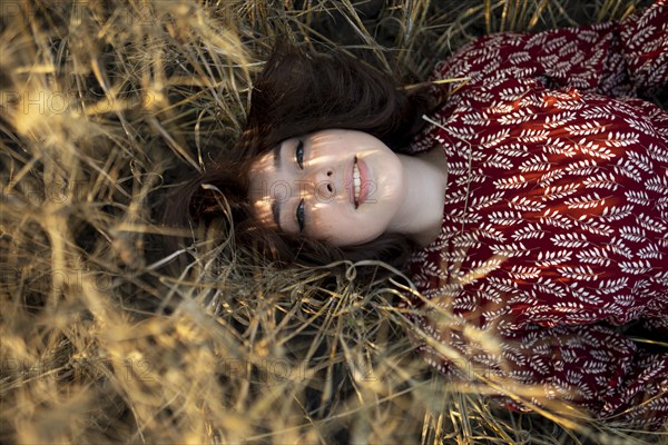 Directly above view of woman lying on cereal plants in field