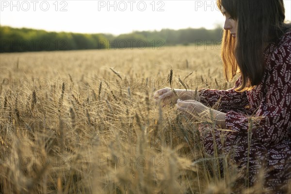Side view of woman touching cereal plant in field