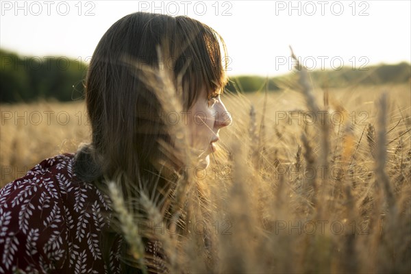 Portrait of young woman looking at agricultural field at sunset