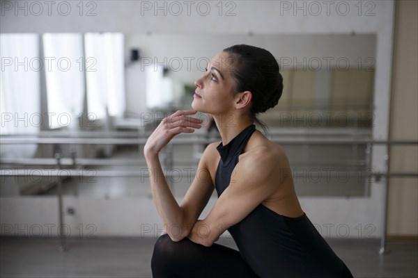 Ballerina in graceful pose looking up and touching chin
