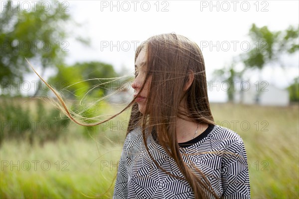 Blonde young woman with tousled hair in field
