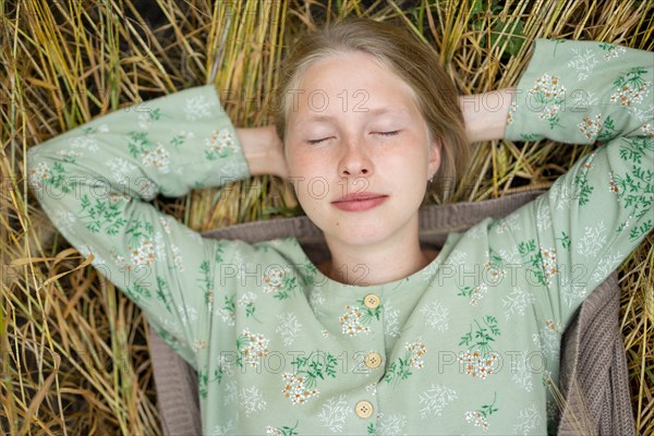 Young woman lying down in field with eyes closed