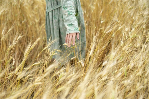 Young woman wearing dress standing in field of wheat