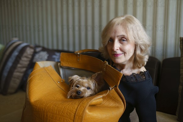 Portrait of woman with Yorkshire terrier sitting in bag