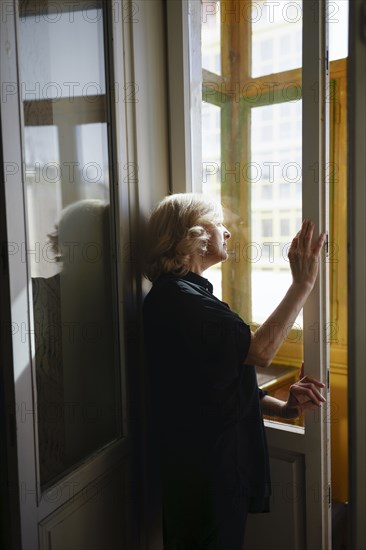 Woman standing by window and looking outside