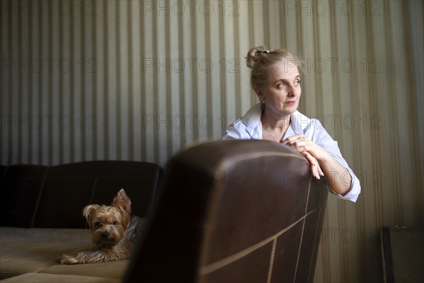Woman sitting on sofa with Yorkshire terrier at home