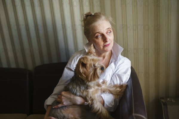Woman sitting on sofa and holding Yorkshire terrier