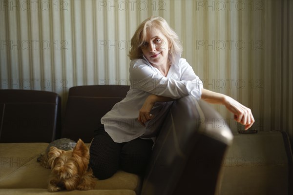Woman leaning on sofa next to Yorkshire terrier in living room