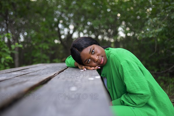 Woman leaning on picnic table and looking at camera