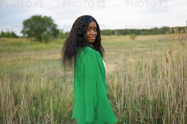 Brunette woman wearing green blouse and standing in field