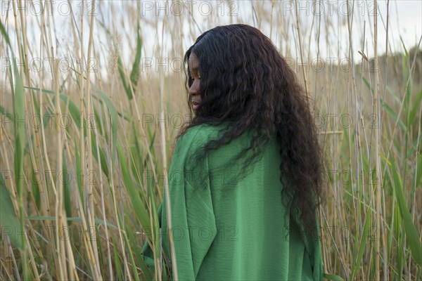 Brunette woman standing among long grass in field