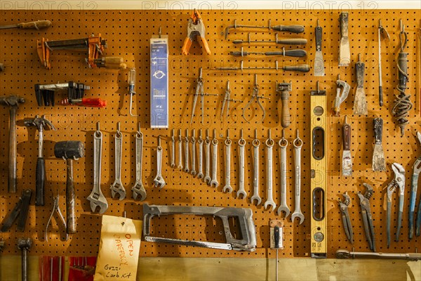 Tools on pegboard hooks on wall of wood and metal shop