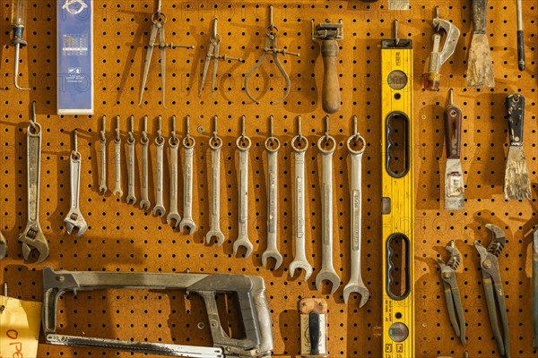 Tools on pegboard hooks on wall of wood and metal shop