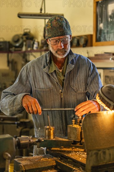 Senior artisan wood and metal craftsman works with tools in workshop