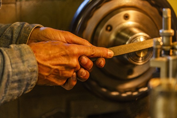 Hands of senior wood and metal craftsman using tools in workshop