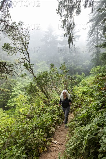 Senior woman hiking on hill with nordic walking poles