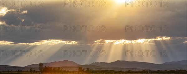 Rays from setting sun shining on fields and hills