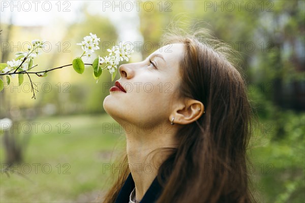 Beautiful woman smelling flower in orchard