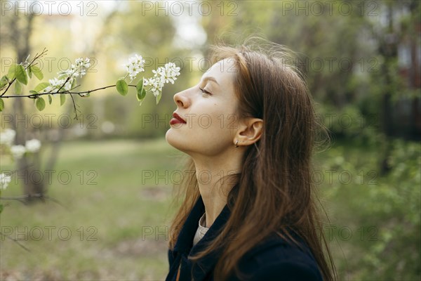 Beautiful woman smelling flower in orchard