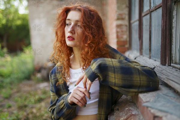 Redhaired woman posing next to old brick house