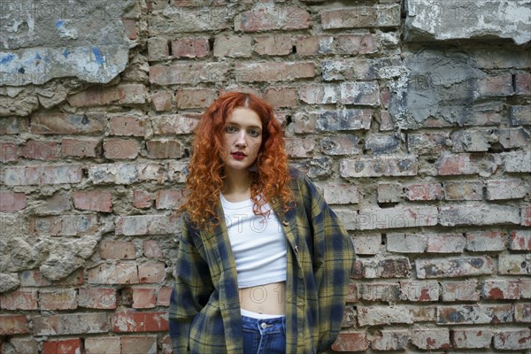 Redhaired woman posing next to old brick house