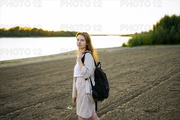 Portrait of thoughtful woman standing on beach at sunset