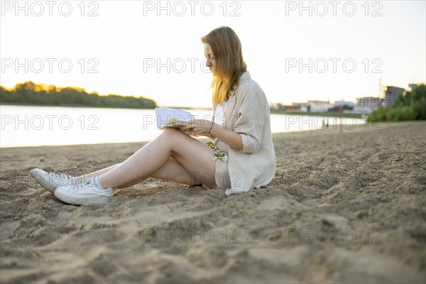 Woman reading book beach at sunset