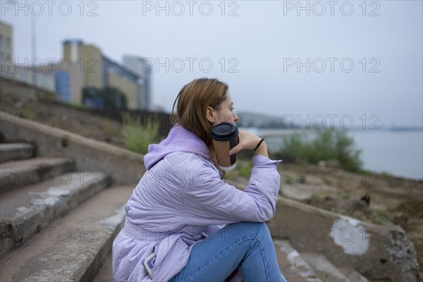 Thoughtful woman sitting on steps and looking at river